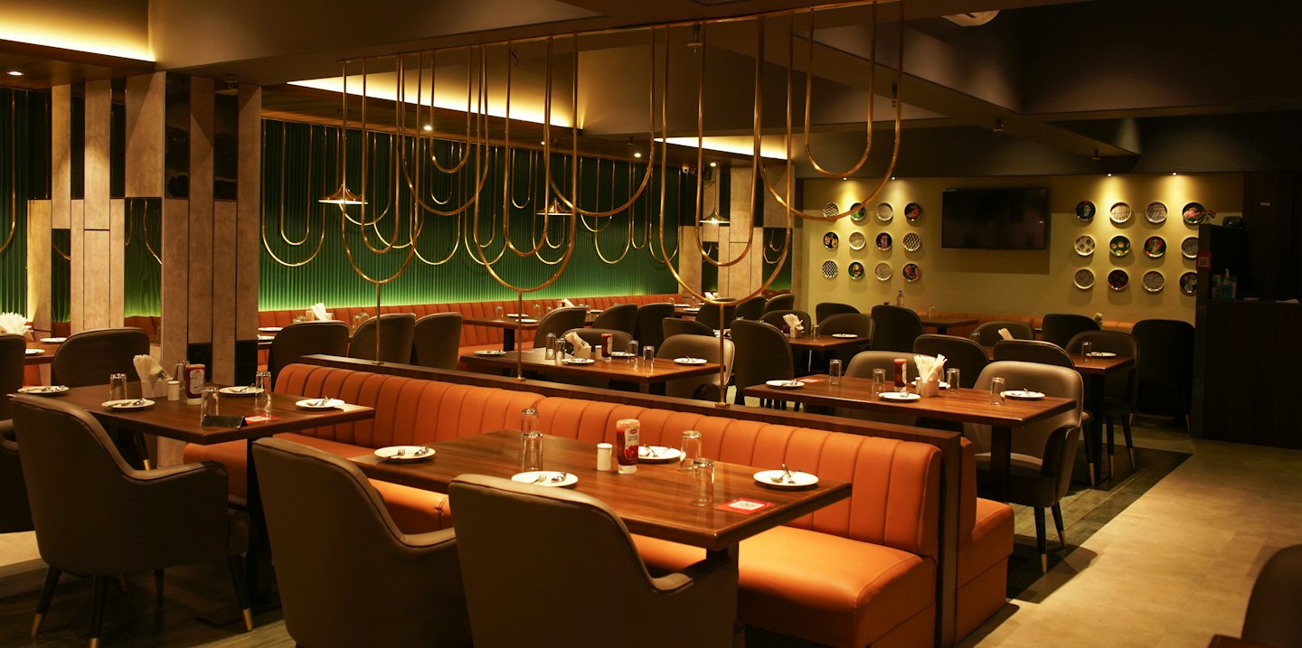 Moderner Restaurant-Essbereich mit Holztischen und gepolsterten Sitznischen.