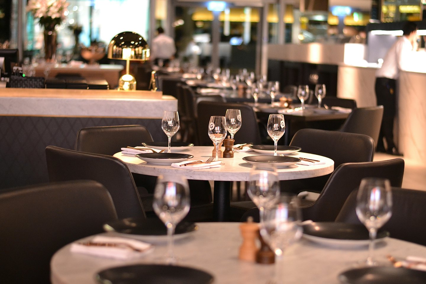 Elegantes Restaurant-Esszimmer mit Marmortischen und Ledersesseln.