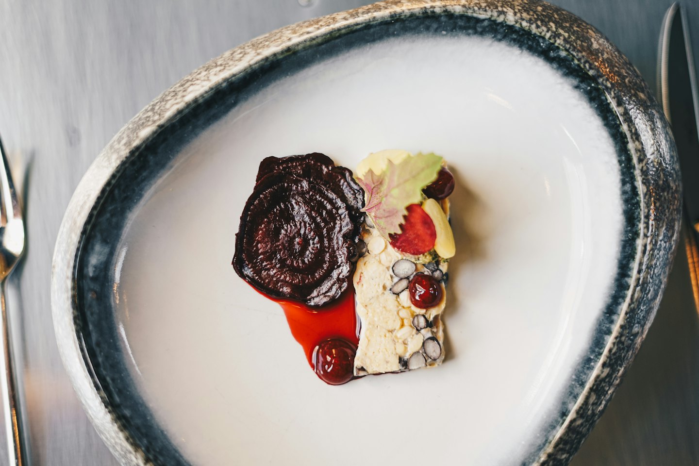 Gourmet-Gericht mit roter Sauce und Beeren auf einem weißen Teller.