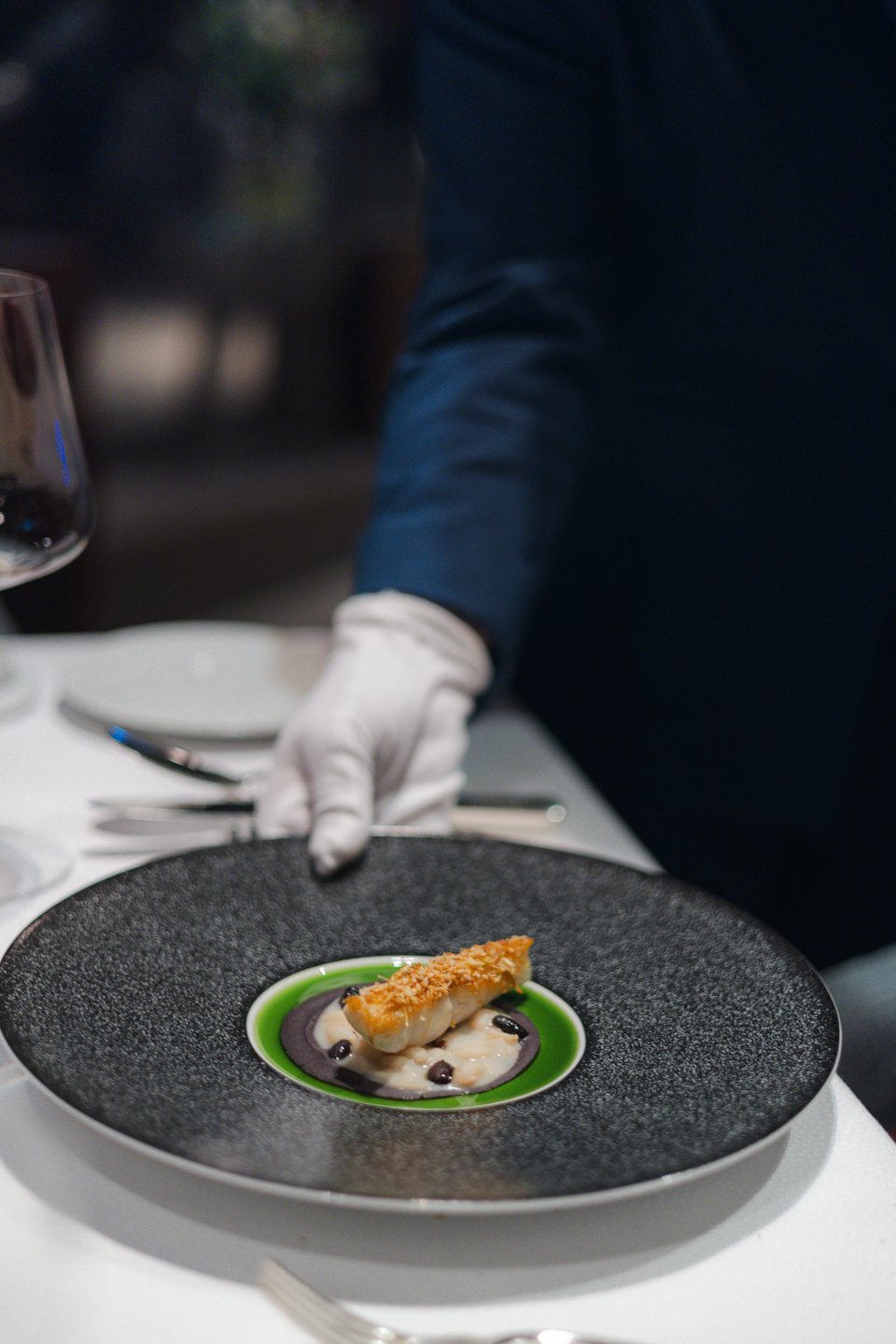 Ein Kellner stellt ein Gourmet-Menü auf einen Esstisch.